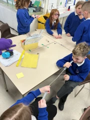 Year 3 children around a table creating a pneumatic system using rubber pipe and syringes
