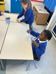 two children from Year 3 sat at a table discussing how to make a pneumatic system