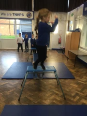 Year 3 Hedgehogs class jumping into the air off a  gymnastics bench