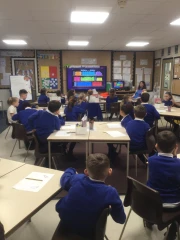 Year 3 Hedgehogs class RE lesson with children listening to a visitor from the local church talking about the books of the bible.