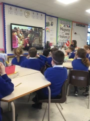 Year 3 Woodpeckers class watching The Good Samaritan film on a TV screen with a visitor from the local church