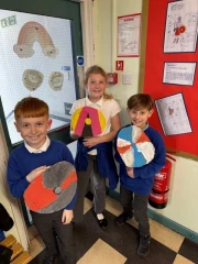 Three children holding painted Viking shields.