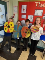 Four children holding painted Viking shields.